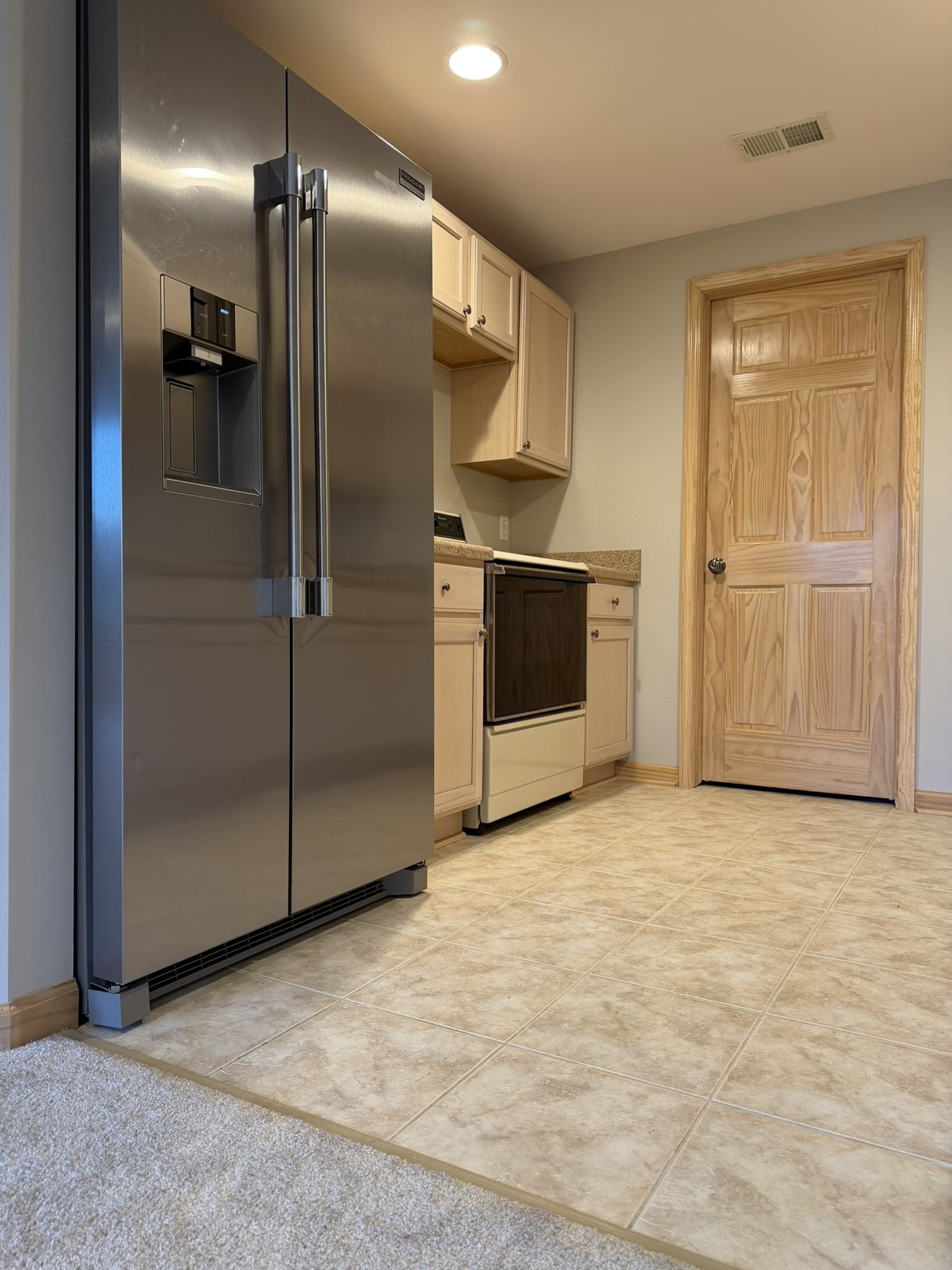 Lower level kitchen — stainless side-by-side fridge and range