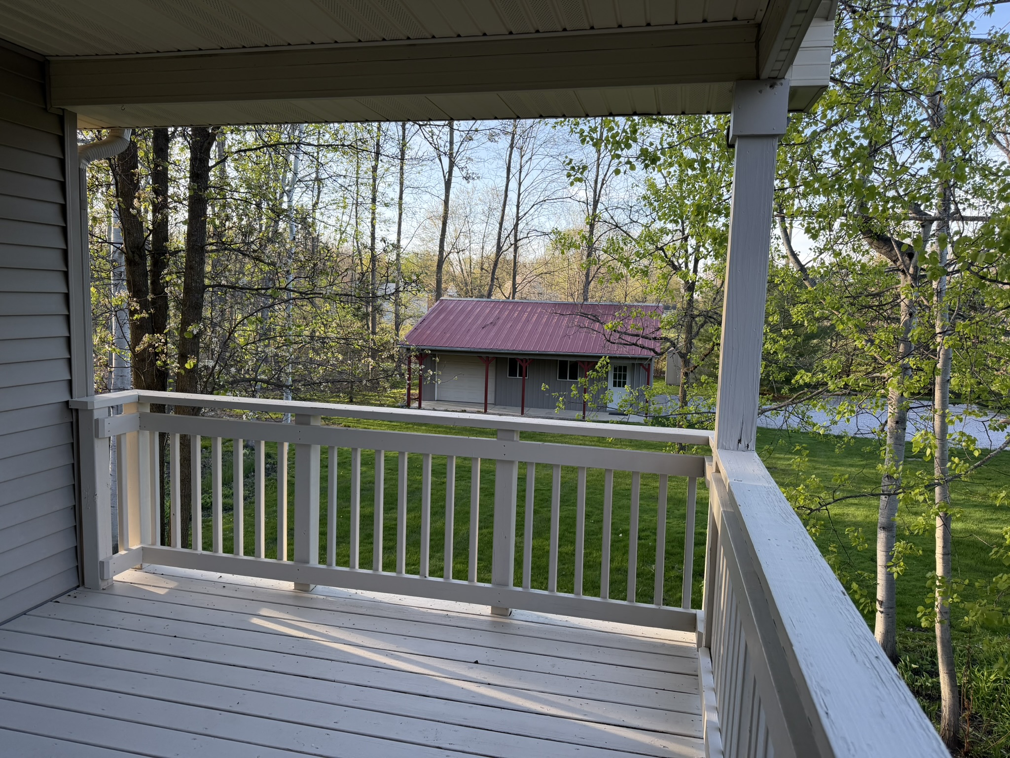 Covered deck off main floor with wooded views and pole barn